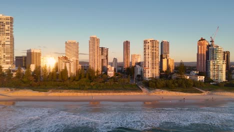 aerial view of gold coast's skyline at sunrise, highlighting skyscrapers and beach with warm morning light reflections