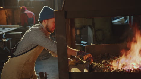 blacksmith heating iron rod in charcoal forge