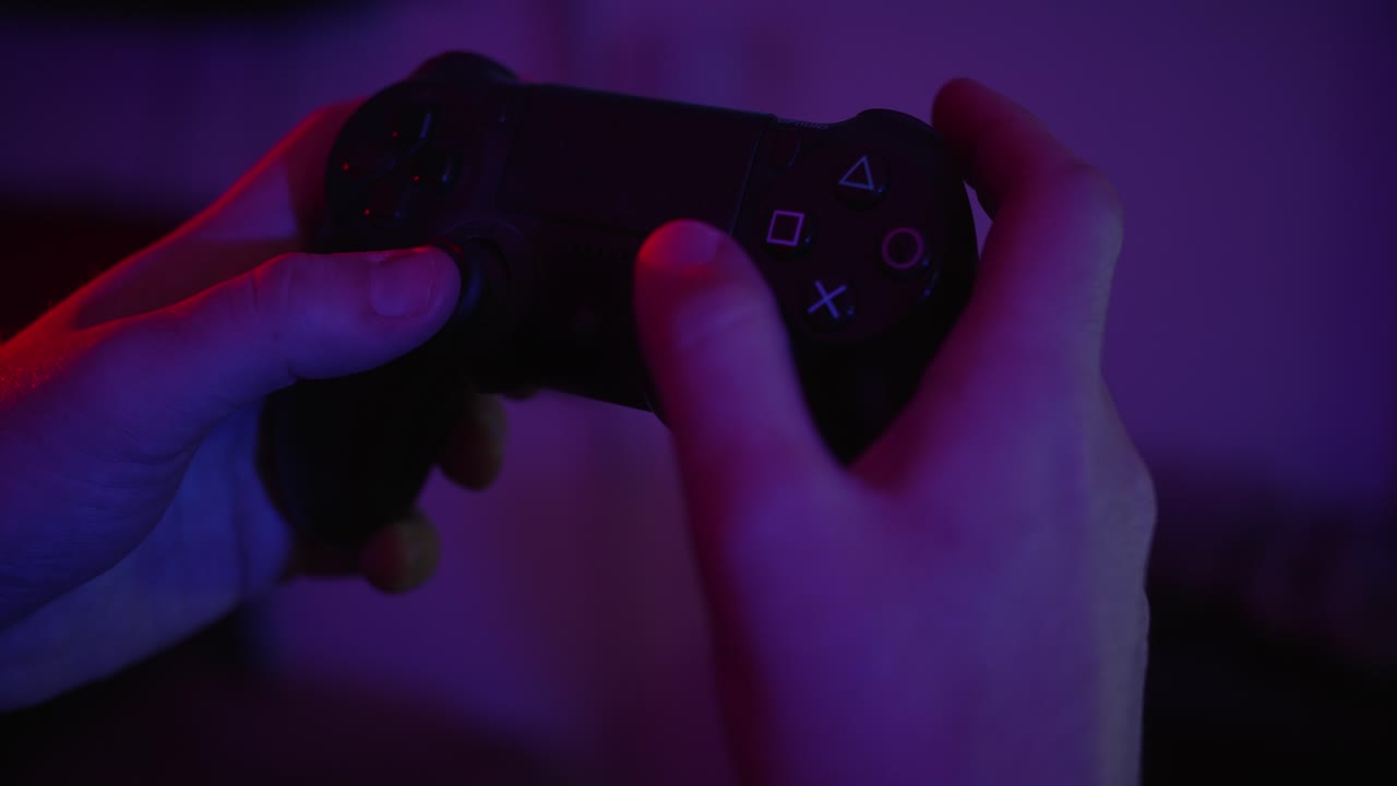 Close-up of Hands Playing Video Game with Controller in Neon Light