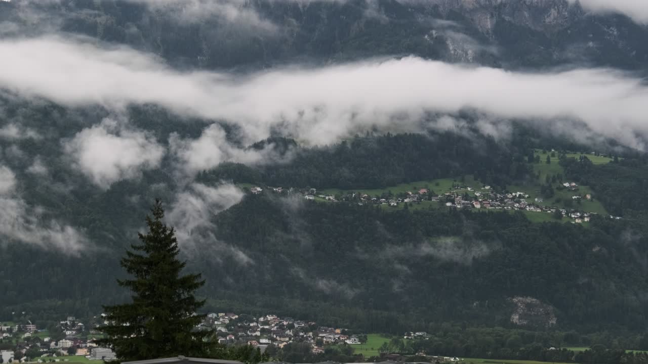 Panoramavy Liechtenstein med hus på gröna kullar i molniga Alperna