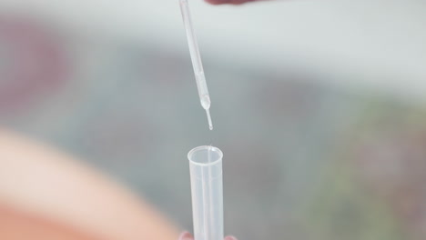 gotas de líquido de la pipeta en un tubo de ensayo de plástico para la prueba de covid-19