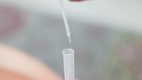 fluid drops from pipette into plastic test tube for covid-19 testing