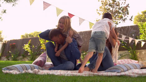 family having fun on blanket in garden