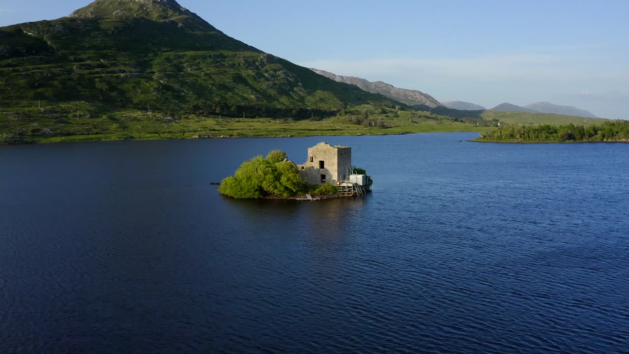 Ballynahinch Lake, Connemara, County Galway, Ireland, July 2021. Drone faces east while ascending and orbiting a small island with a ruined building
