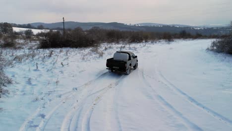 camioneta cargada que conduce lentamente a través de una carretera cubierta de nieve durante el invierno - de mano, plano medio