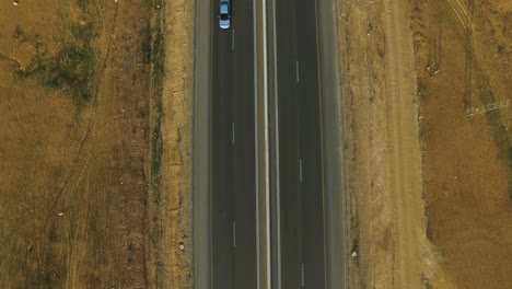 vista superior aérea: volando sobre una carretera asfaltada en medio del desierto amarillo