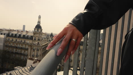 cerca de la mano de una mujer joven subiendo escaleras al aire libre, con el paisaje urbano de parís en el fondo, francia