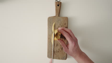 Hands-cutting-ripe-pear-in-slices-on-a-wooden-cutting-board-with-sharp-knife