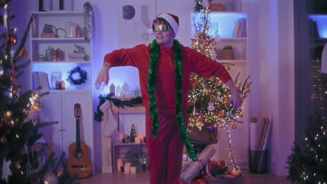 hombre exhilarado con sombrero de papá noel y gafas de sol bailando en casa