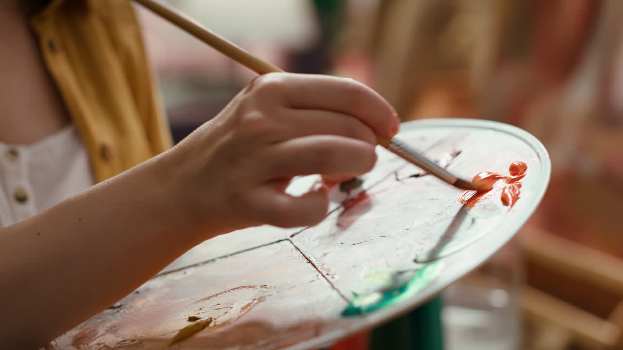 Close-up of artist's hand mixing paint on a palette
