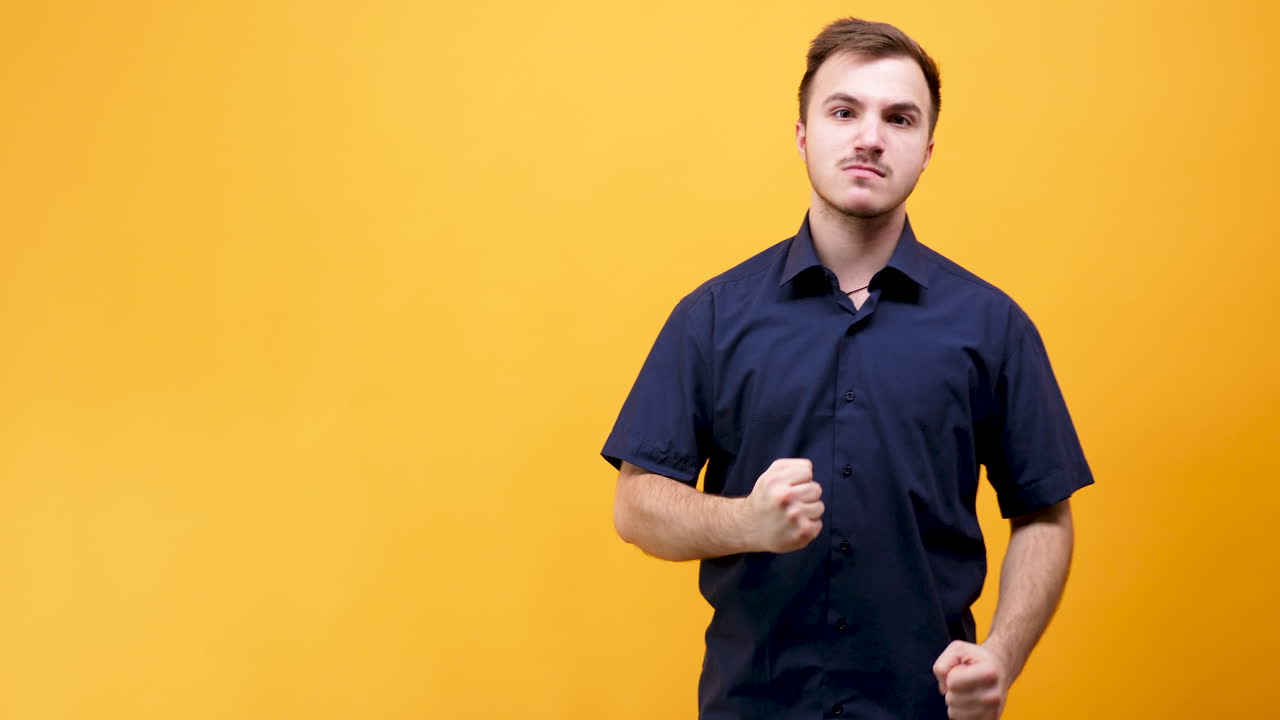 Man in blue shirt dancing on yellow background
