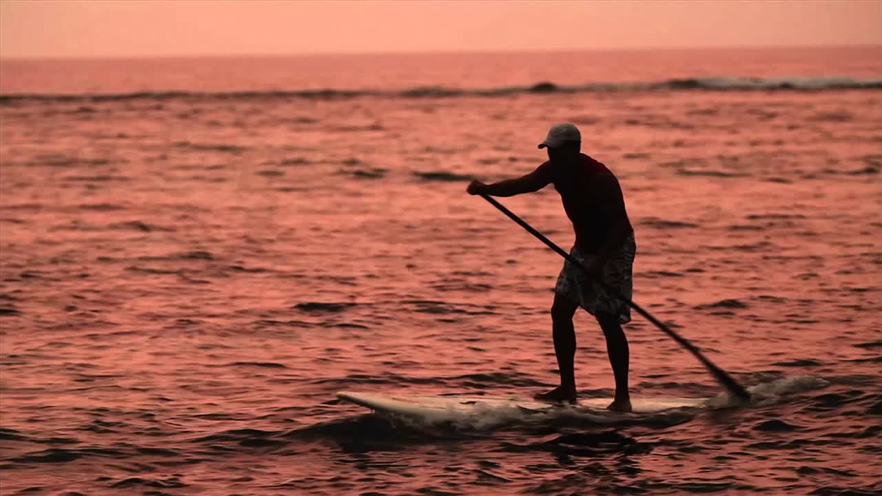 한 남자가 sunet에서 라군을 가로질러 서핑을 한다