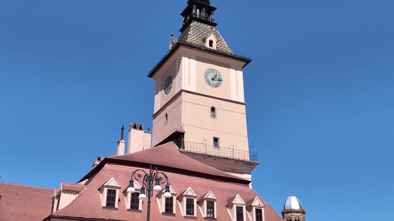 La Casa del Consiglio di Brașov che mostra architettura storica e una torre dell'orologio, con acqua di una fontana che zampilla in primo piano