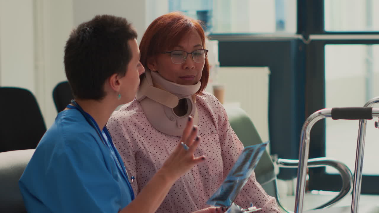 Nurse explaining X-ray results to patient with cervical collar in hospital waiting room