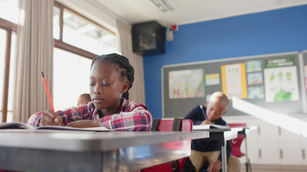 Smiling girl sitting at desk in school classroom, enjoying her lesson