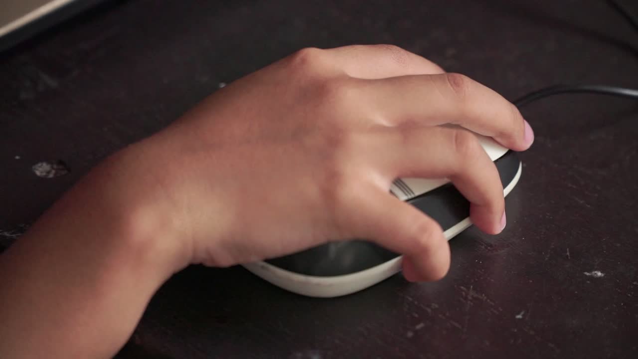 Child hand controlling mouse during online learning. Education, technology use, and remote study
