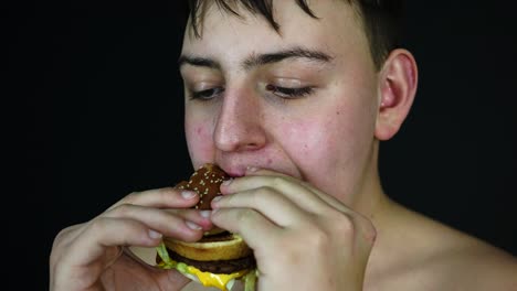 joven con sobrepeso comiendo hamburguesa, dieta poco saludable y concepto de obesidad, de cerca