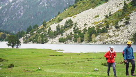 couple of friends male trekker crossing a green meadow valley in aigüestortes national park catalan pyrenees spain