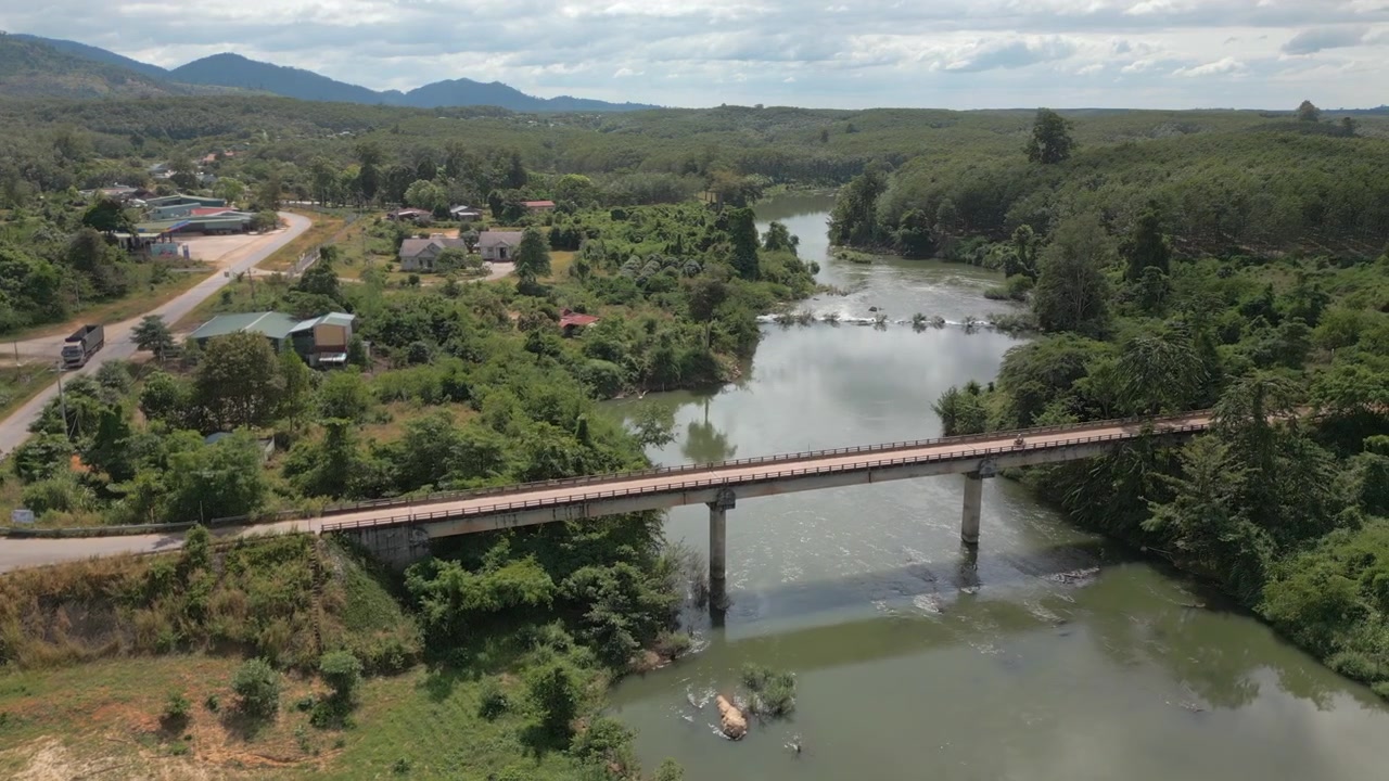 Scooter attraversa ponte su fiume nel Vietnam rurale, provincia di Kon Tum, vicino al confine con la Cambogia. Ripresa con drone in tracking 4K 30FPS