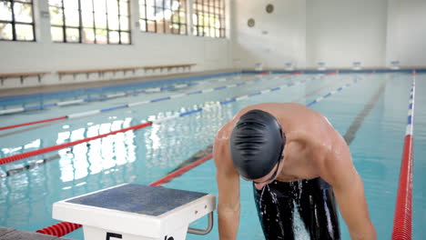 preparing to dive, swimmer in swim cap and goggles at indoor pool, copy space