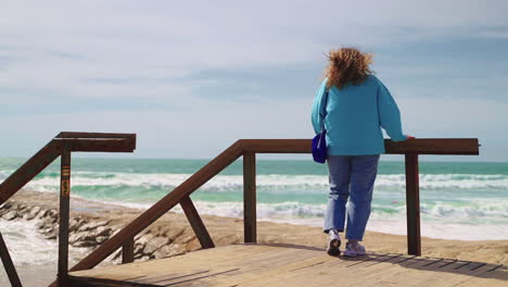 woman watching the ocean from a wooden pier