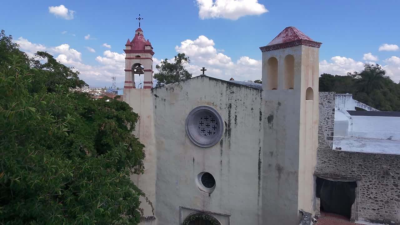 Aerial: church in Oaxtepec with blue cloudy sky during the day in Morelos, Mexico, crane down drone shot