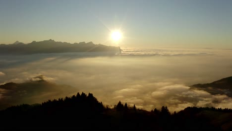 órbita aérea alrededor de una colina rodeada por un mar de nubes al atardecer, suiza