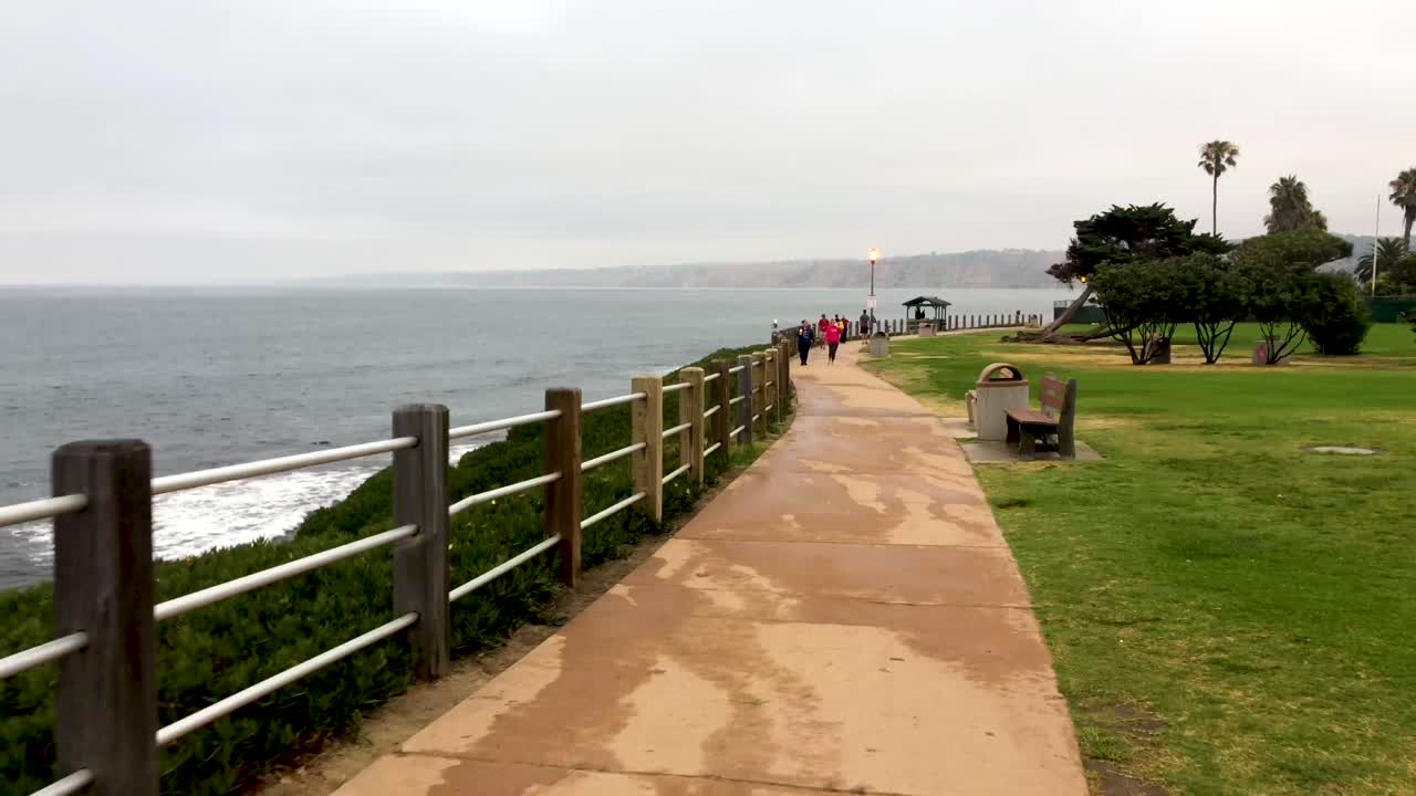 People Walking on a Coastal Path on a Cloudy Day