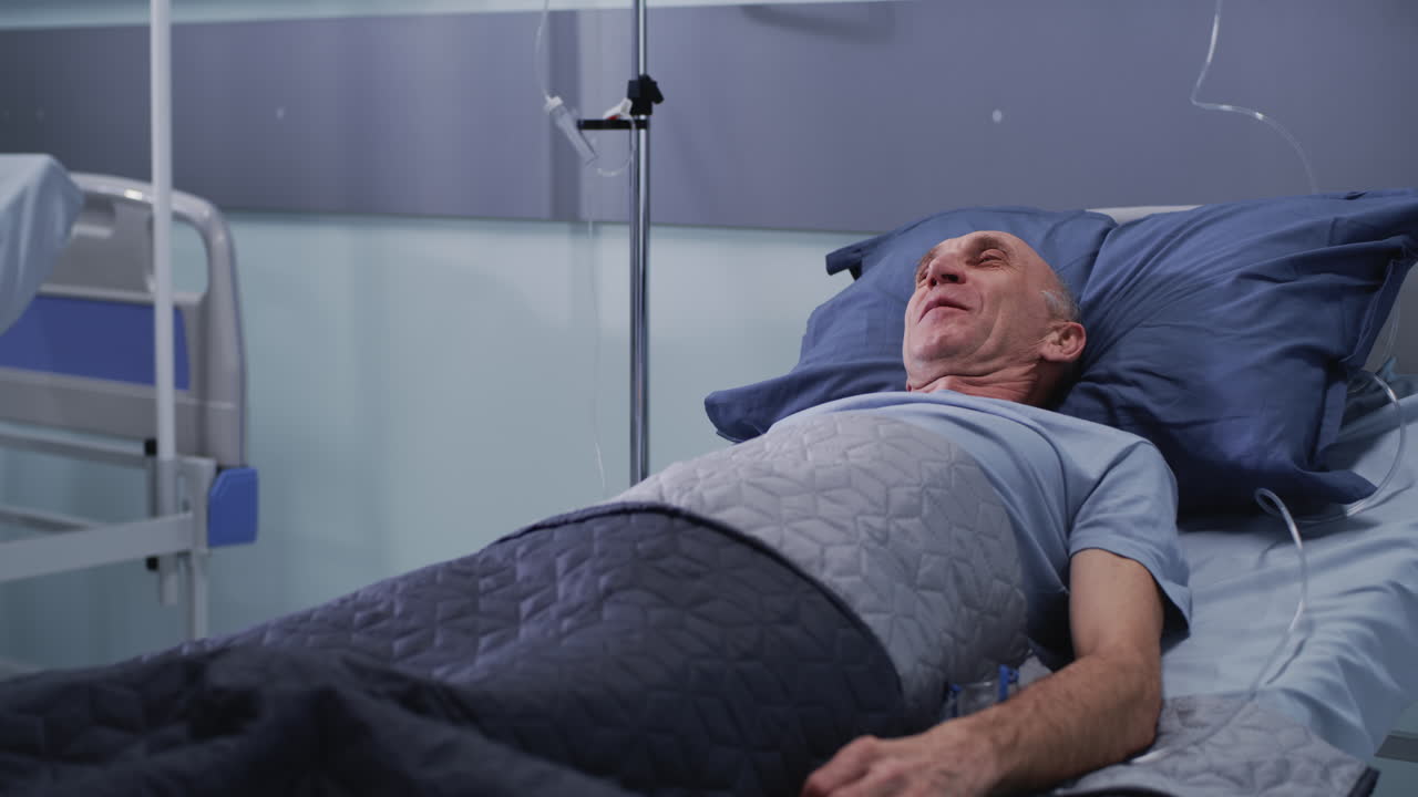 Healthcare Professional in PPE Attends to Elderly Patient in Hospital