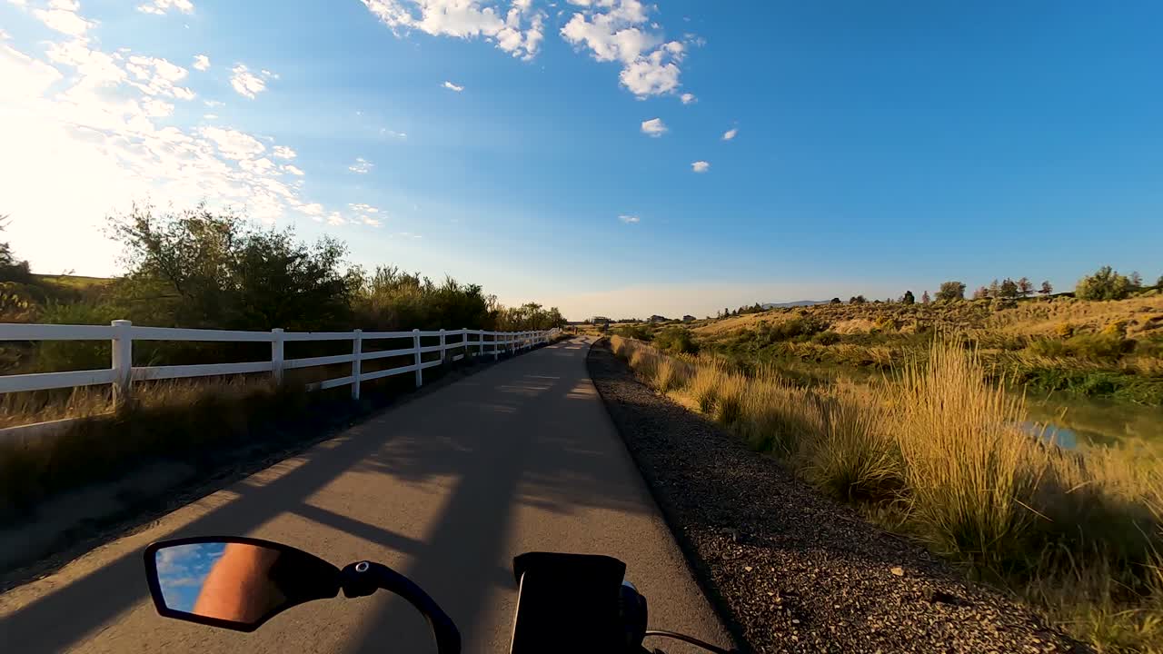 Riding a bicycle along a nature trail beside a river with the sky reflecting off the water