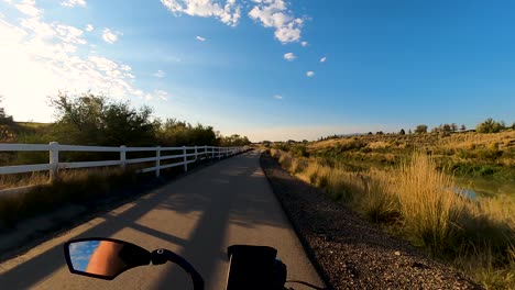 riding a bicycle along a nature trail beside a river with the sky reflecting off the water