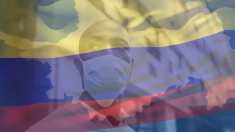 animation of flag of colombia over african american man with face mask