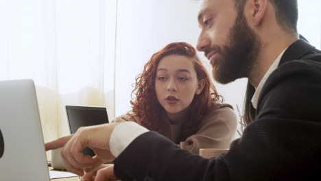 Hombre-Y-Mujer-Debatiendo-Mientras-Miran-Una-Computadora-Portátil-Durante-Una-Reunión-De-Equipo