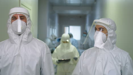 médicos con ropa de protección caminando por el hospital y hablando