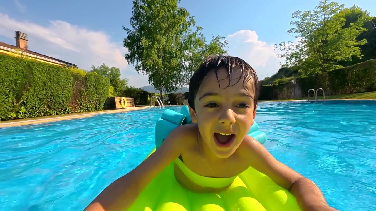 Happy Young Boy Floating and Smiling in a Swimming Pool on a Sunny Day