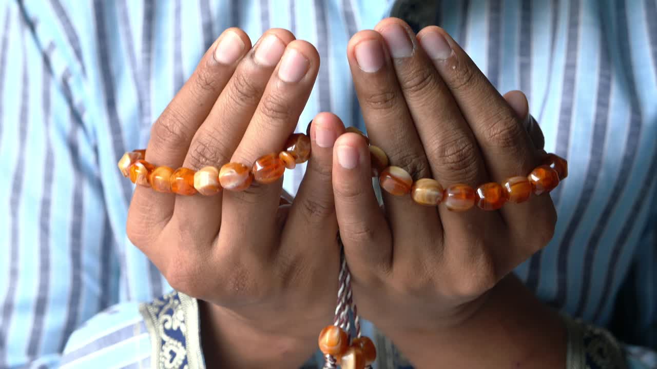 manos en oración con cuentas de oración