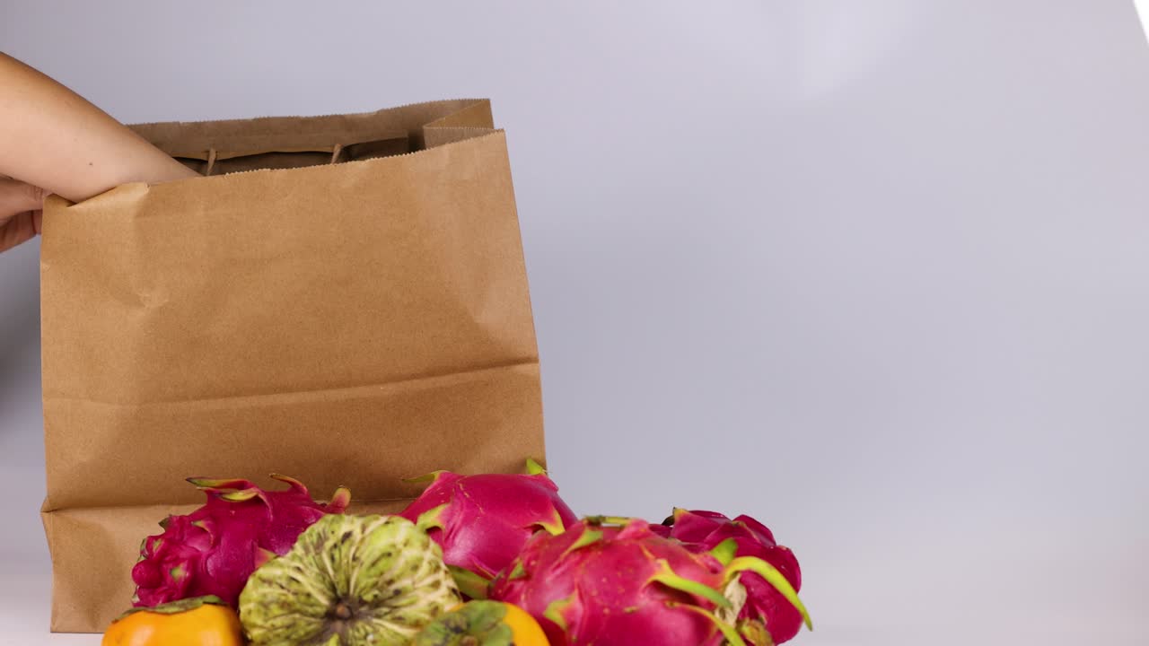 손 은 과일 을 종이 가방 에 넣고 있다