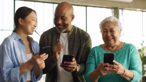 a diverse group of three engaged in mobile technology: a young woman, a middle-aged man, and an older woman enjoying their smartphones together