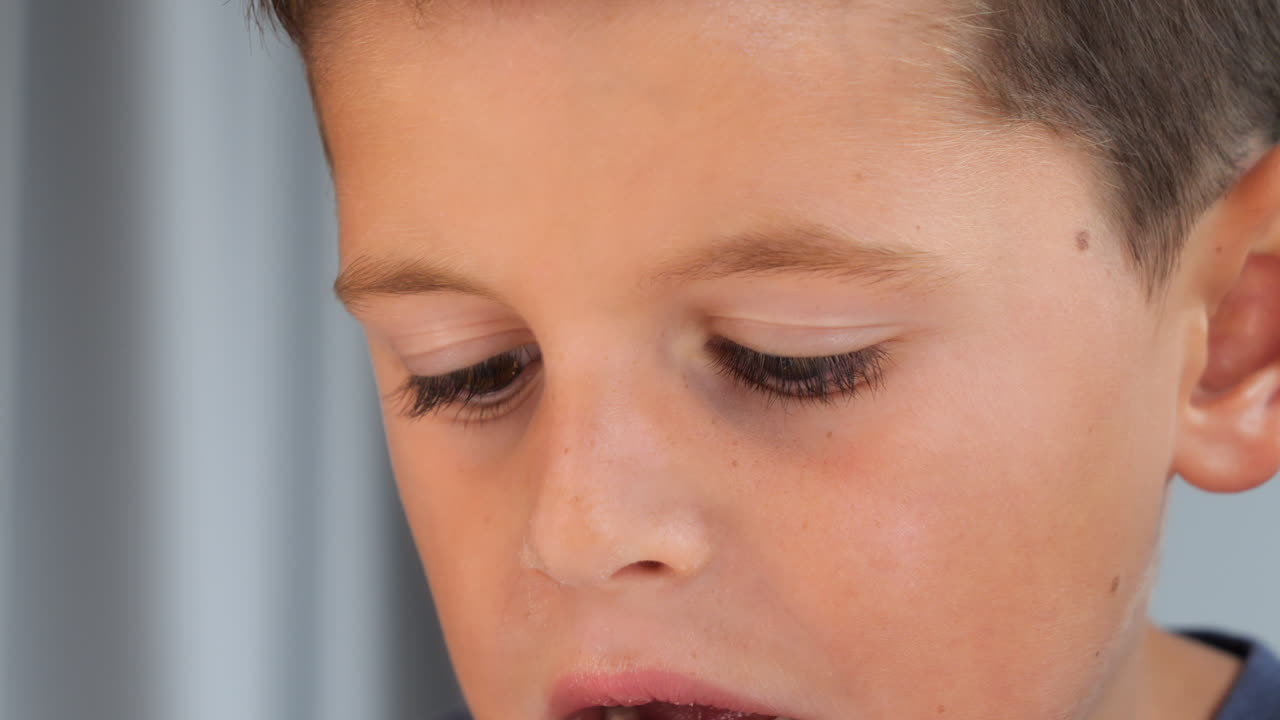 Young Boy Pulls Out Baby Tooth with Paper Towel - Close Up