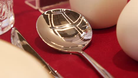 close-up of a shiny spoon reflecting its surroundings on a red tablecloth