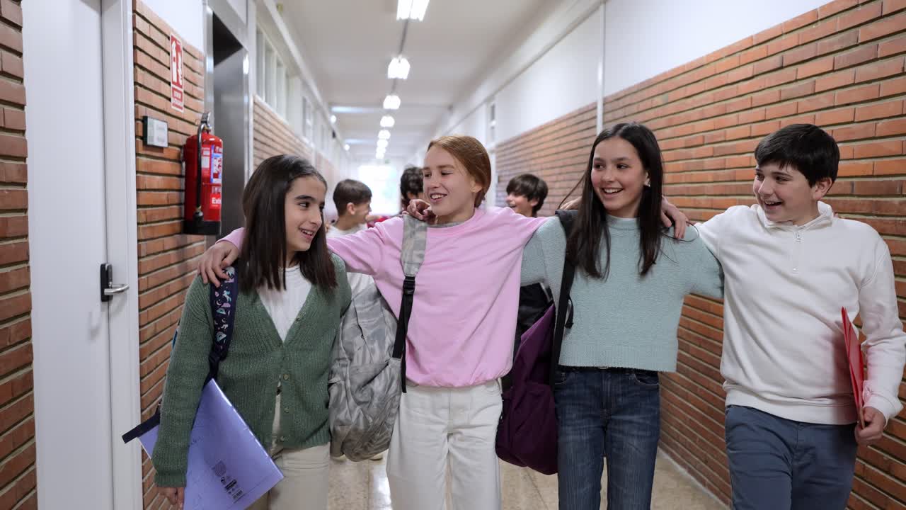 Estudiantes sonrientes caminando del brazo por el pasillo de la escuela