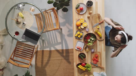 woman in headphones cooking food and dancing at home