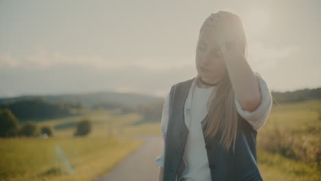 tired blond woman near meadow against sky