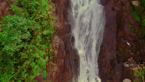 Witness-the-majestic-Bijagual-Cascades-as-the-drone-swiftly-retreats,-showcasing-the-splendor-of-this-natural-wonder-in-the-heart-of-Costa-Rica's-lush-wilderness