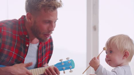 padre y hijo pequeño jugando con instrumentos en casa, de cerca