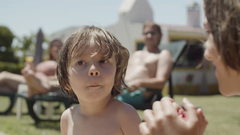 lindo niño sentado cerca de la piscina y comiendo dulces