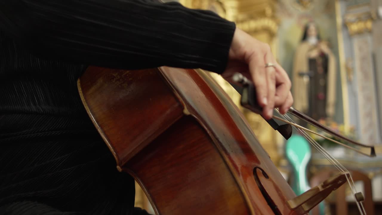 primer plano de un músico tocando un violonchelo en un interior de iglesia bellamente decorado