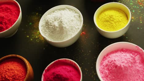 video of multi coloured powder in bowls with copy space on black background