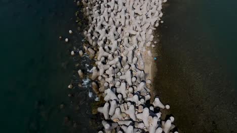 Aerial-View-of-Grey-Jetty-Stones-in-Greece-Port-surrounded-by-dark-blue-ocean-water