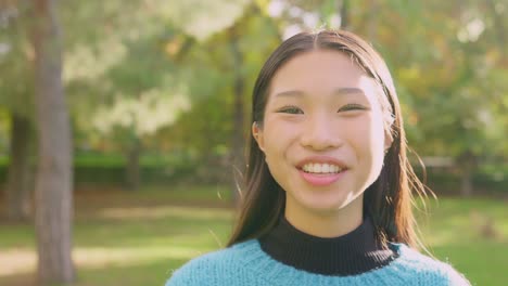 young asian woman smiling in a park